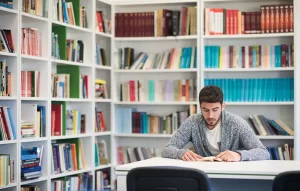 portrait-of-student-while-reading-book-in-school-library_11913894